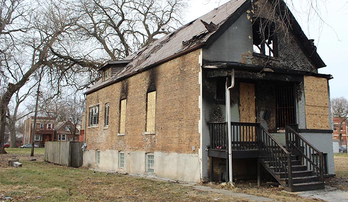 derelict brick house with fire damage and boarded-up windows