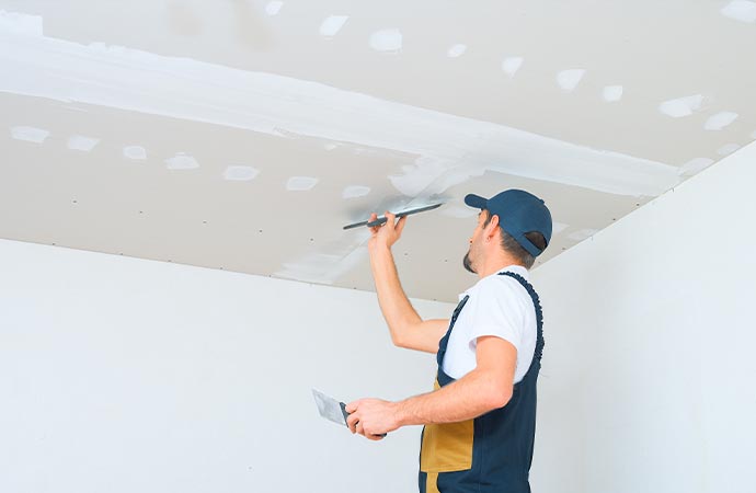 Worker working on the drywall ceiling